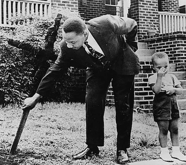 Martin Luther King y su hijo retiran una cruz quemada de su patio. (1960)