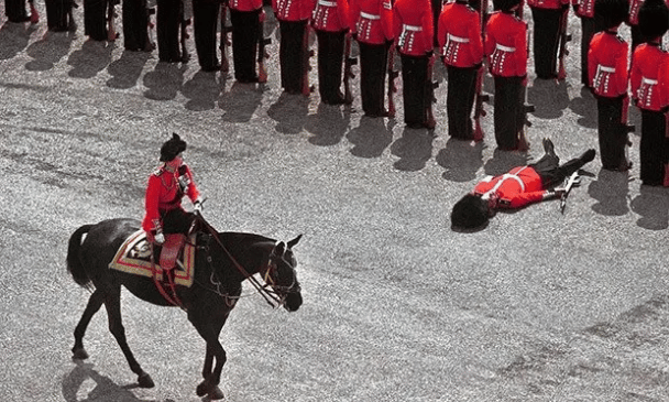 Un Guardia Real pierde el conocimiento al paso de la Reina Isabel II durante un desfile de colores en junio de 1970 en Londres.