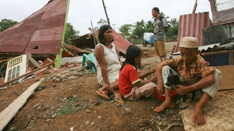 Una familia se sienta cerca de su casa dañada por el terremoto en el pueblo de Lais, a unos 50 km de la ciudad de Bengkulu, el 13 de septiembre de 2007, en la provincia de Bengkulu, isla de Sumatra, Indonesia. (Crédito de la imagen: Dimas Ardian / Stringer a través de Getty Images)