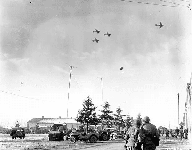 La 101 División Aerotransportada observa cómo los C-47 les arrojan suministros en Bastogne, Bélgica, el 26 de diciembre de 1944.
