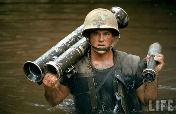 Marine PFC. Phillip Wilson en Vietnam lleva una bazuca a través de un arroyo. 1966.
