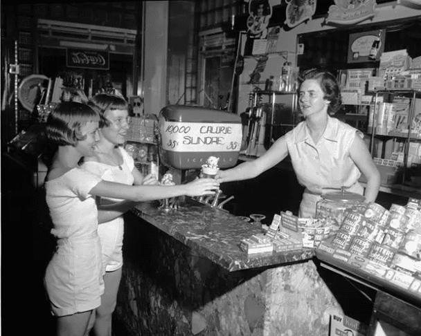 Comprar un '10,000 Calorie Sundae' por 35 centavos en la tienda de Blair Parson en Lynchburg, Virginia. 1950