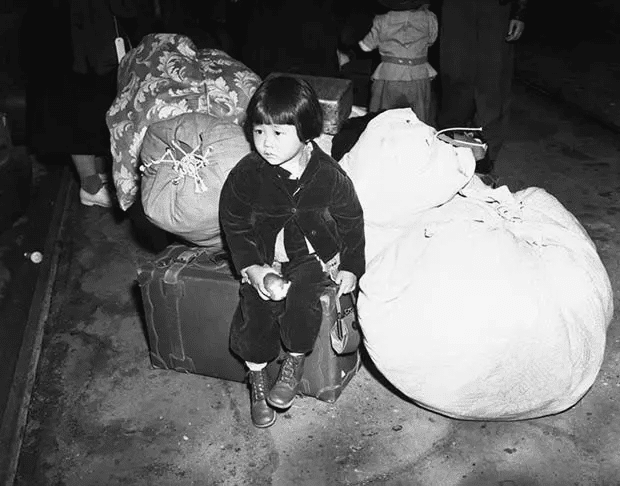 Una niña estadounidense de ascendencia japonesa espera con el equipaje familiar antes de ser evacuada a los campos de internamiento en la primavera de 1942 en California.
