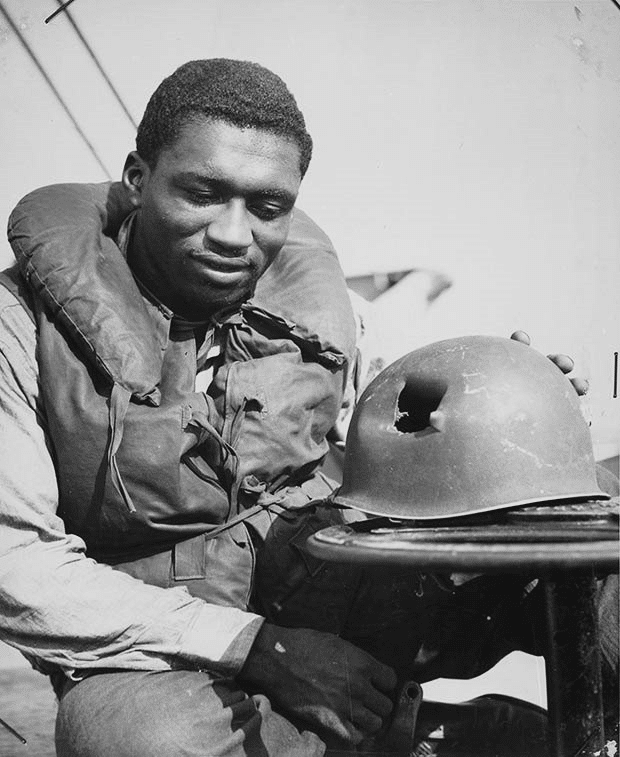 El guardacostas Charles Tyner, bombero de primera clase, inspecciona su casco golpeado por metralla durante el desembarco aliado en el sur de Francia en 1944.